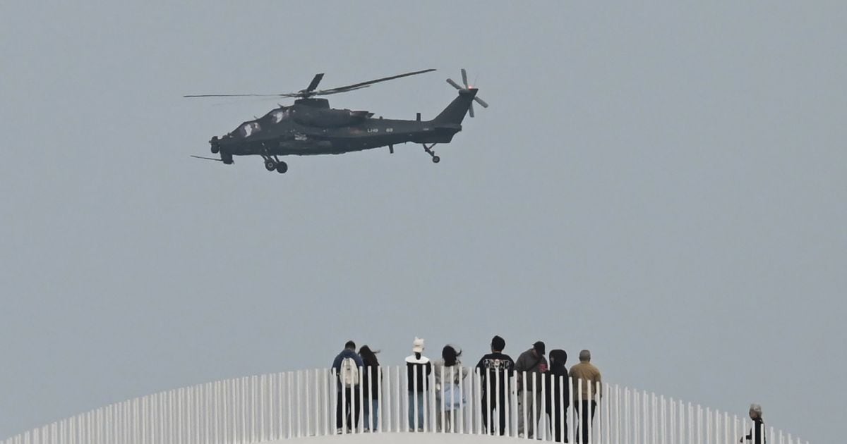 Un hélicoptère militaire survole des touristes à un point d'observation du détroit de Taïwan sur l'île chinoise de Pingtan, point le plus proche de l'île de Taïwan, le 7 avril 2023